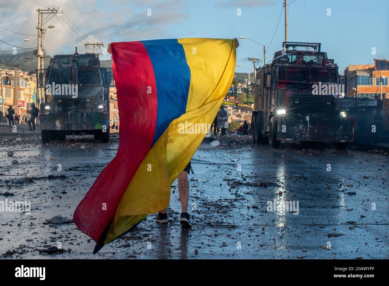 Bogota, Colombia. 21st June, 2021. A demonstrator waves a Colombian flah in the middle of two armored riot tanks as clashes between demonstratros and Colombia's riot police erupt anti-government protest raise in Bogota Colombia against the government of president Ivan Duque, inequalities and abuse of authority by police. Credit: Long Visual Press/Alamy Live News Stock Photo