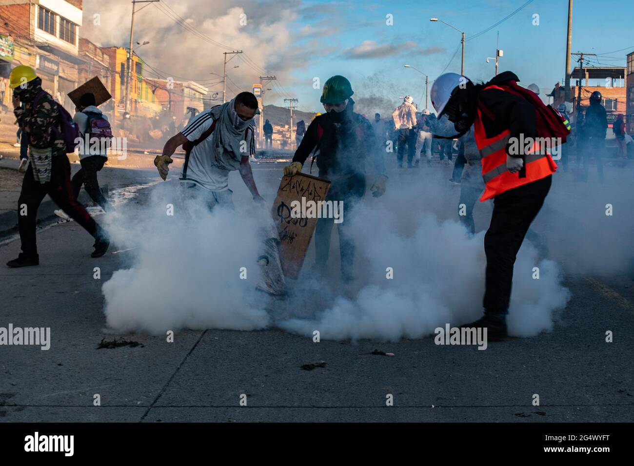 Bogota, Colombia. 21st June, 2021. A group of demonstrators mitigates a tear gas canister as clashes between demonstratros and Colombia's riot police erupt anti-government protest raise in Bogota Colombia against the government of president Ivan Duque, inequalities and abuse of authority by police. Credit: Long Visual Press/Alamy Live News Stock Photo