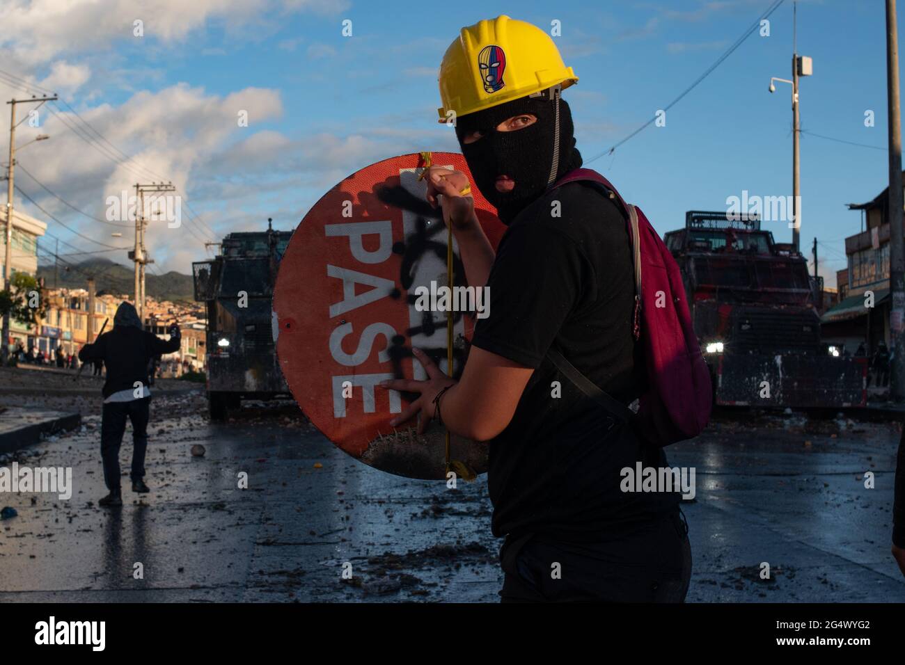 Bogota, Colombia. 21st June, 2021. A demonstrator holds a roadsign as a shield as clashes between demonstratros and Colombia's riot police erupt anti-government protest raise in Bogota Colombia against the government of president Ivan Duque, inequalities and abuse of authority by police. Credit: Long Visual Press/Alamy Live News Stock Photo