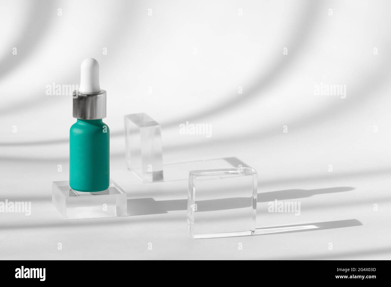 Serum skin care product on background with shadows, hyaluronic acid oil. Cosmetic serum liquid mockup in blue bottle, glass podium decor. Mock up Stock Photo