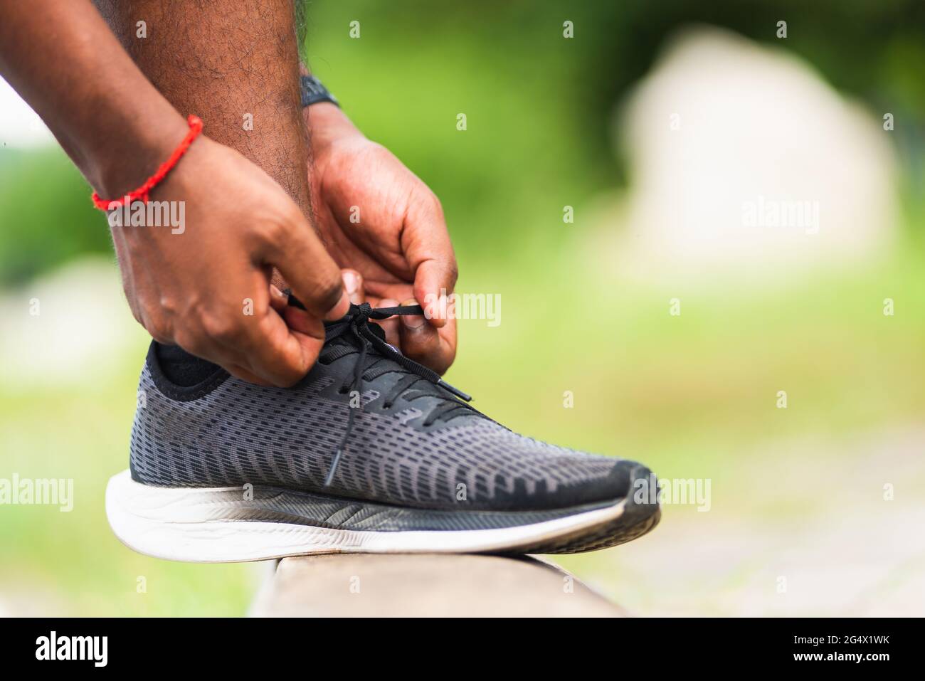 Close up Asian sport runner black man wear watch step on the footpath trying shoelace running shoes getting for jogging and outdoor st Stock Photo - Alamy