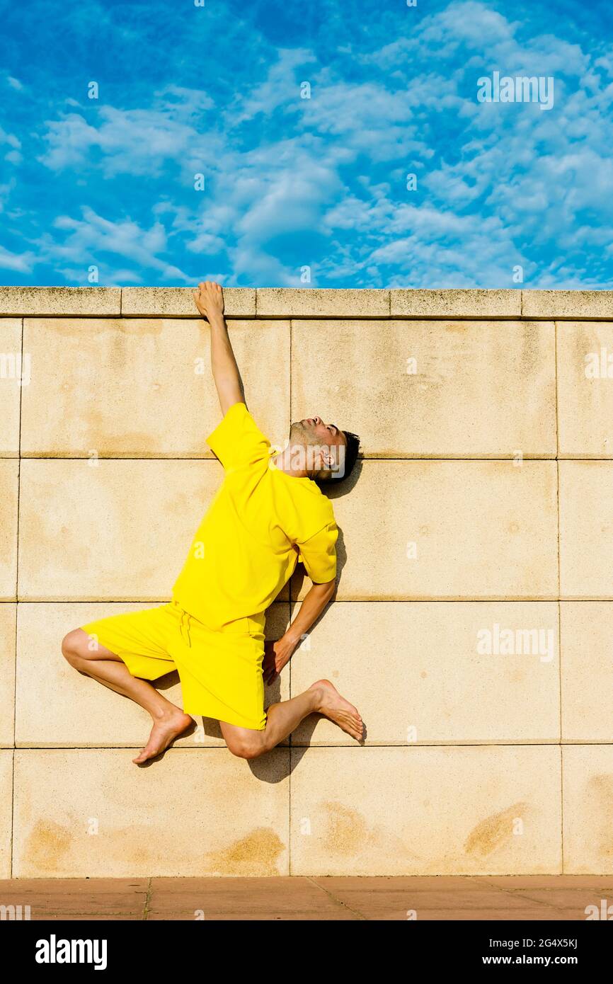Young man hanging on wall Stock Photo Alamy