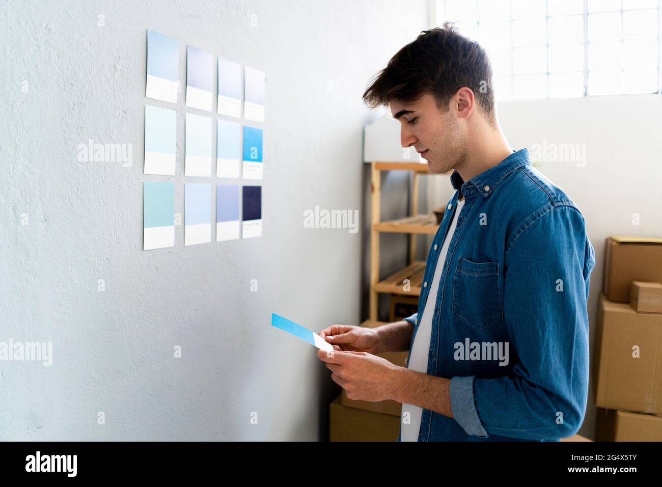 Businessman looking at blue card in front of wall at warehouse Stock Photo