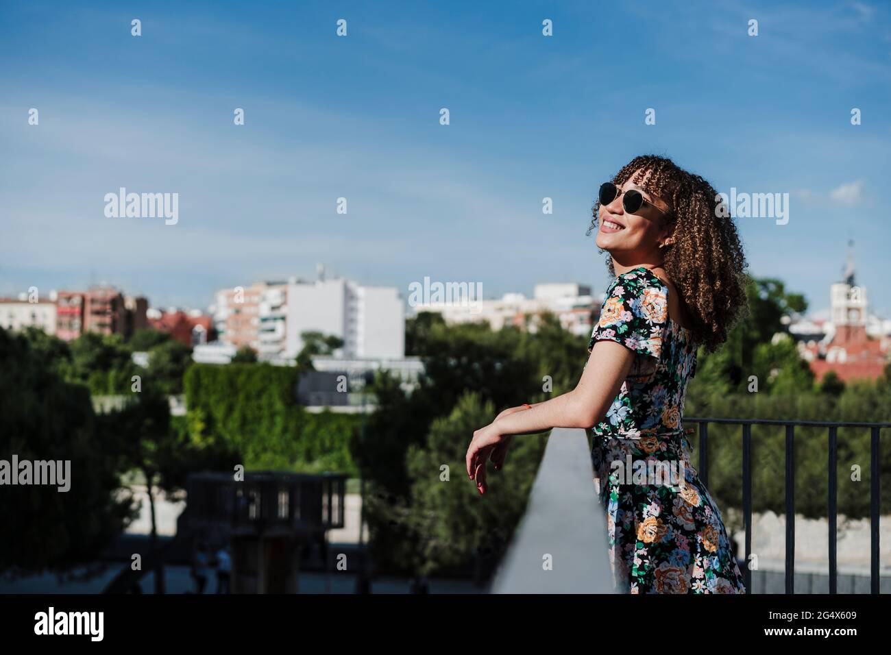 Smiling young woman wearing sunglasses standing by railing Stock Photo