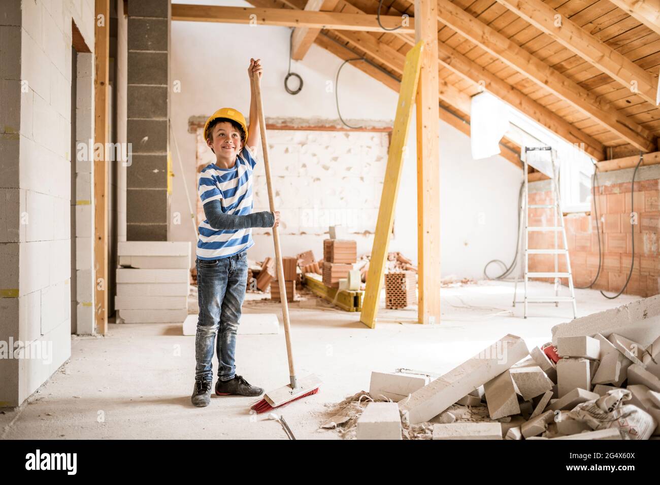 Boy wearing hardhat cleaning house during renovation Stock Photo