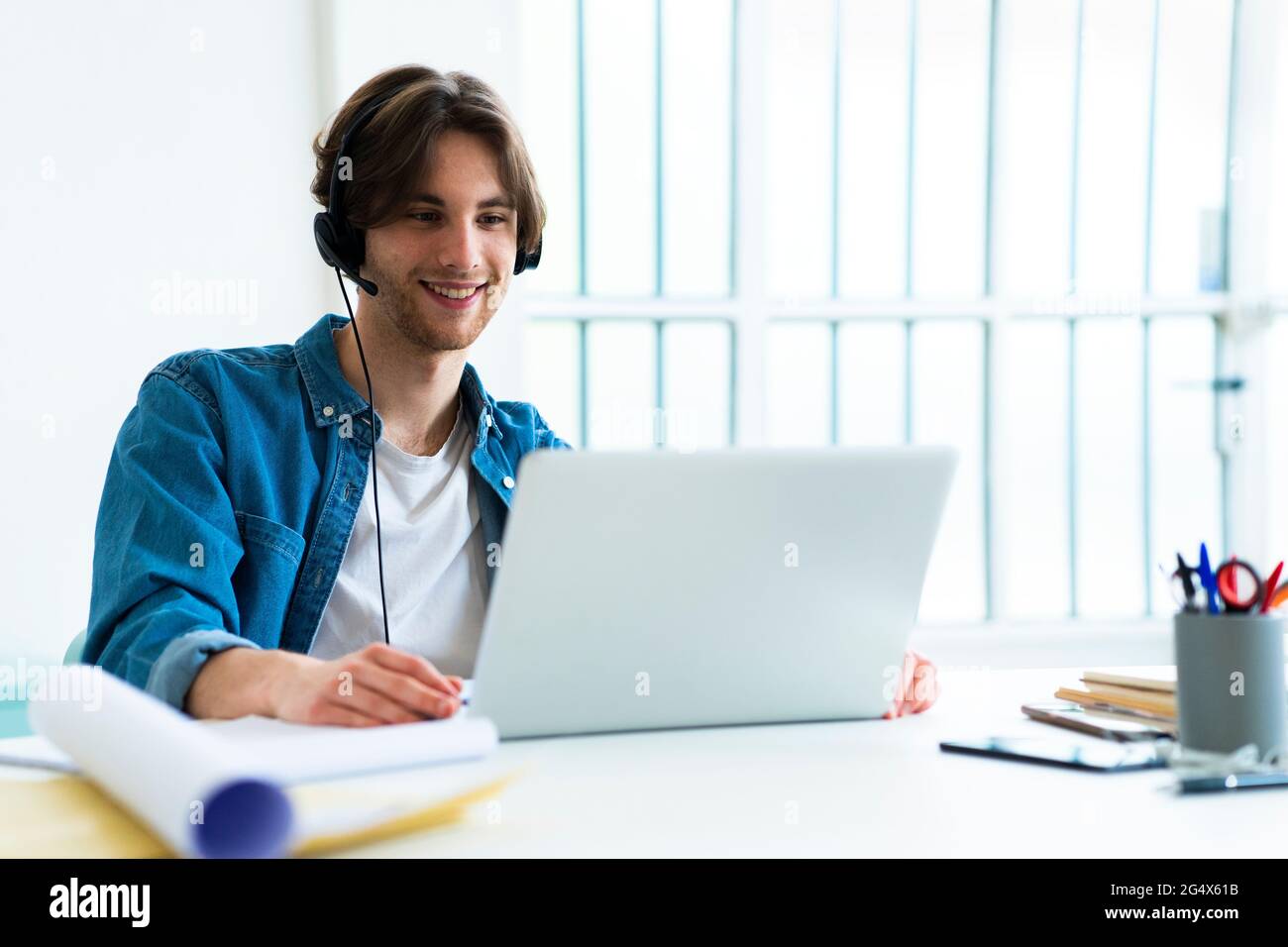 Smiling businessman with headset using laptop while working in office Stock Photo