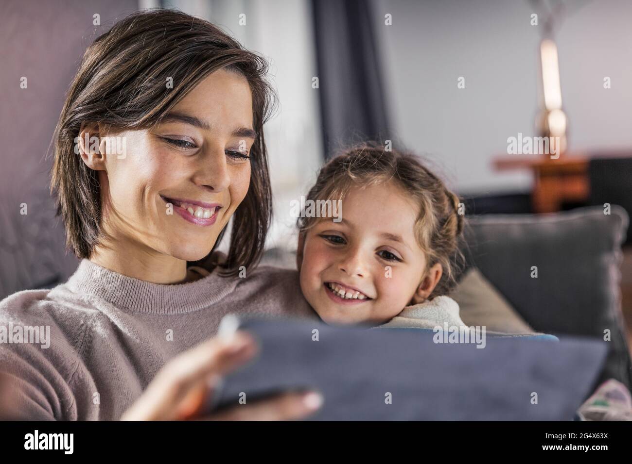 Smiling mother and daughter using digital tablet at home Stock Photo