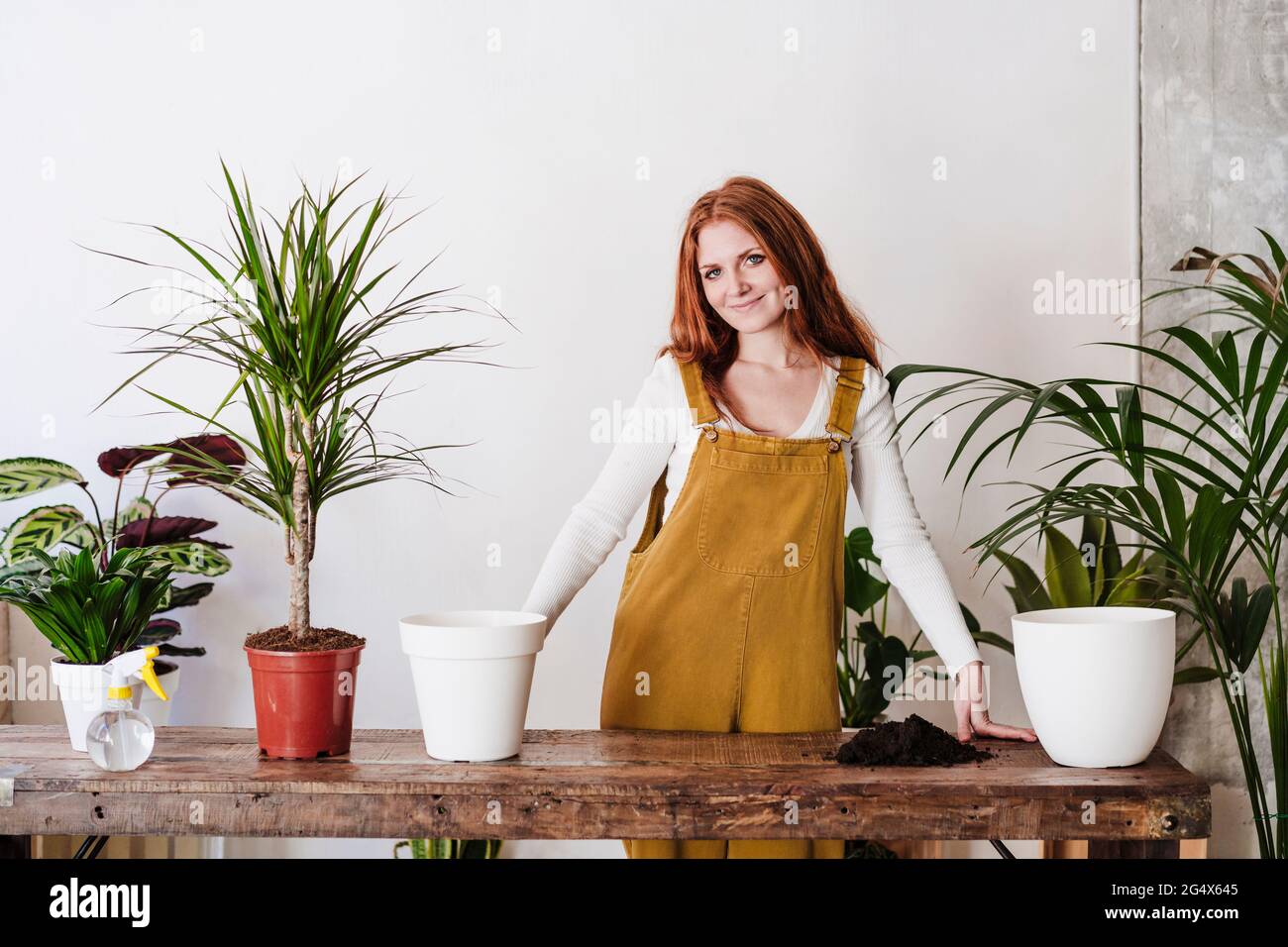 Smiling woman standing in front of table while doing gardening at home Stock Photo