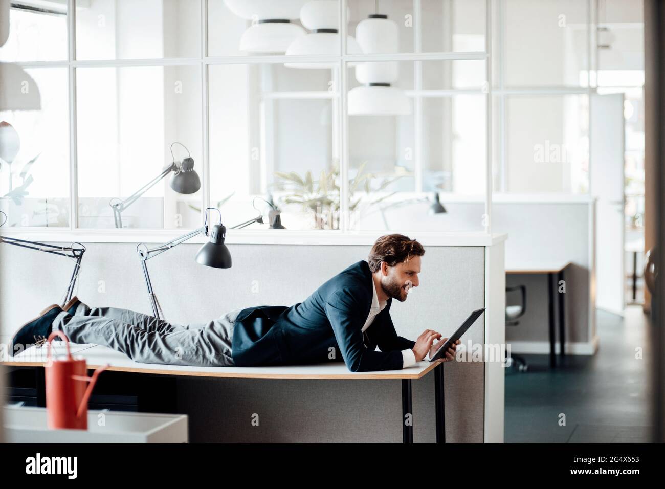 Businessman using digital tablet while lying on table at office Stock Photo