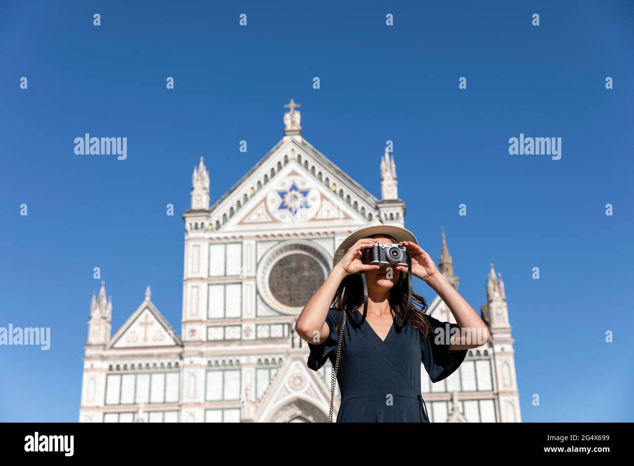 Female tourist photographing through camera in front of Basilica Of Santa Croce, Florence, Italy Stock Photo