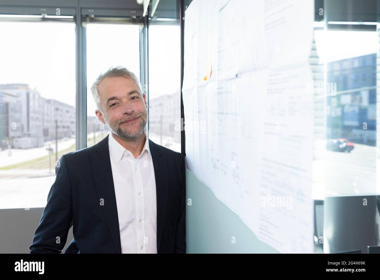 Male professional leaning on business plan at office Stock Photo