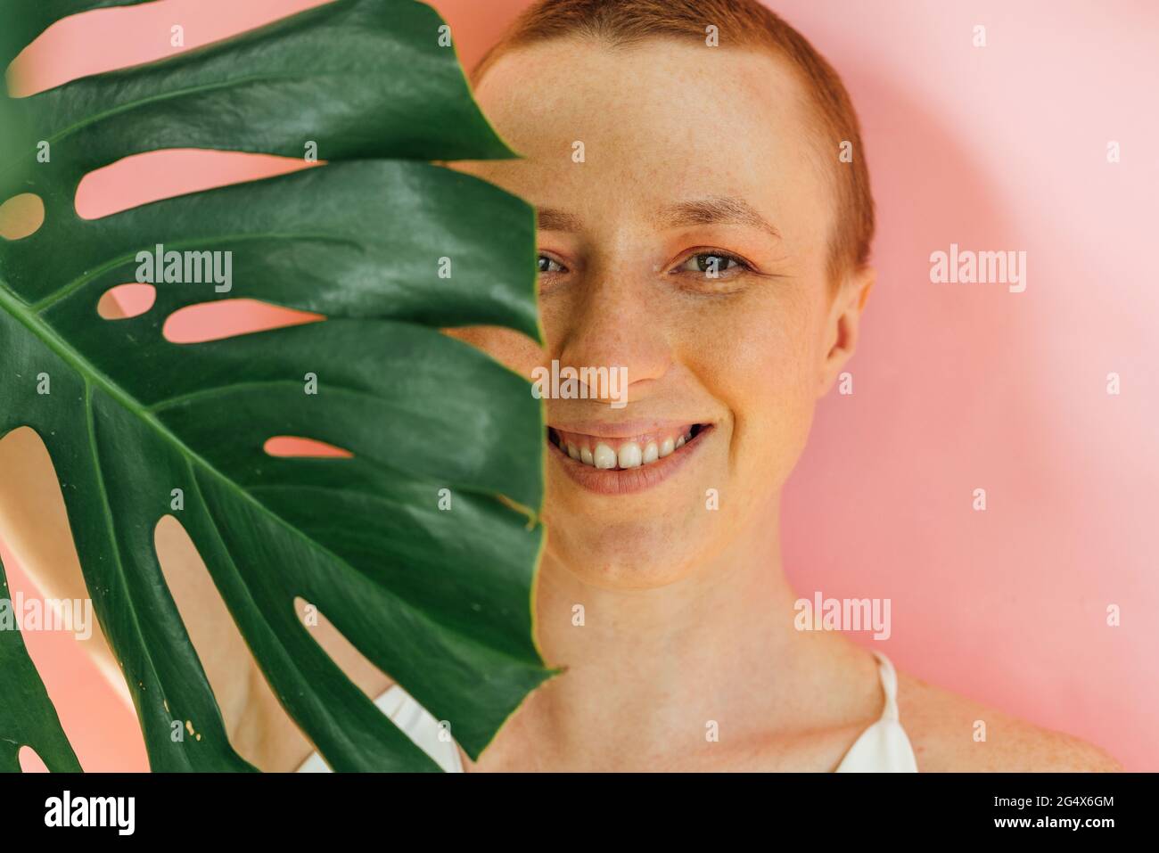 Smiling woman's half face covered with green leaf Stock Photo