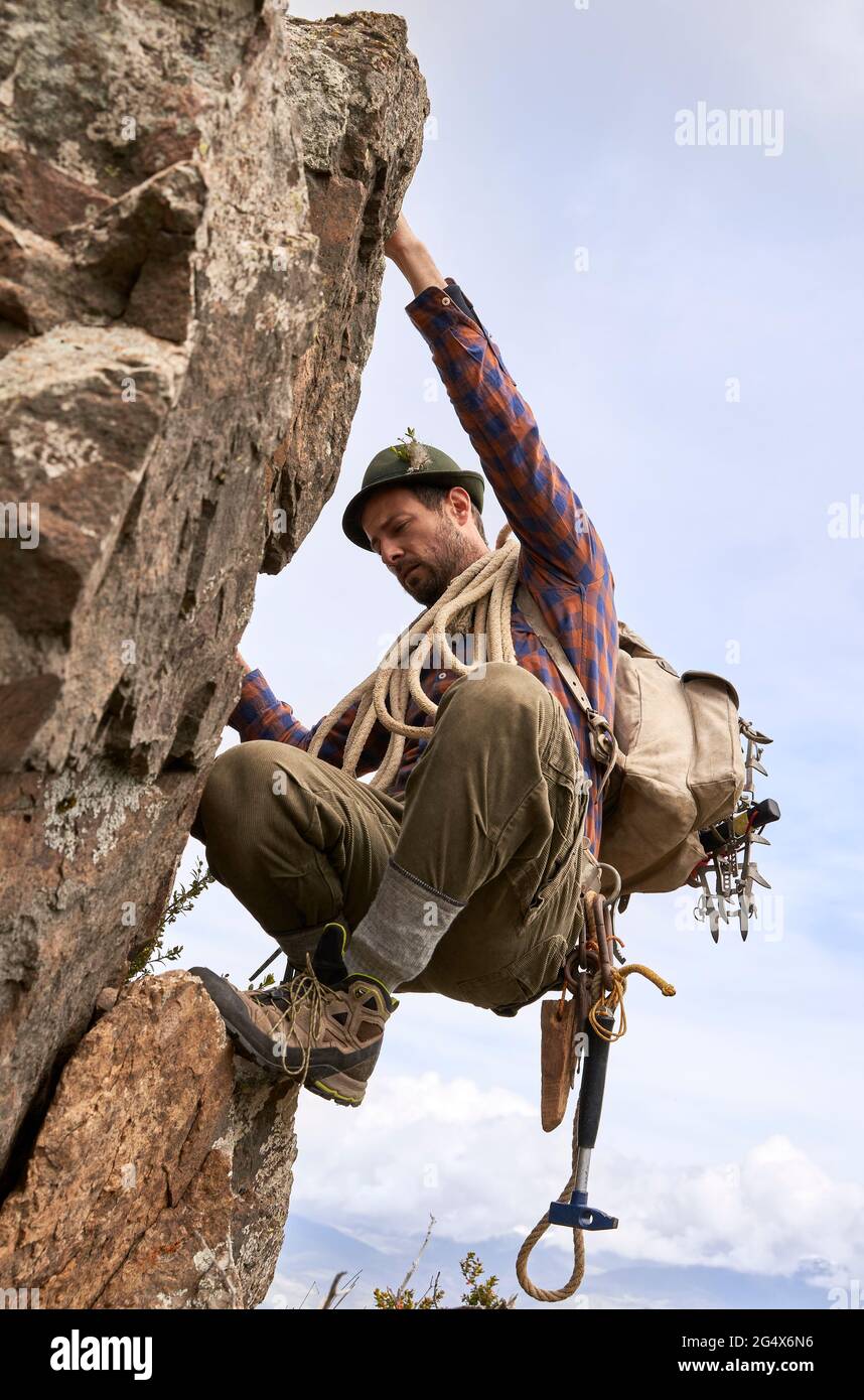 Mid adult mountaineer with backpack and rope climbing rock Stock Photo