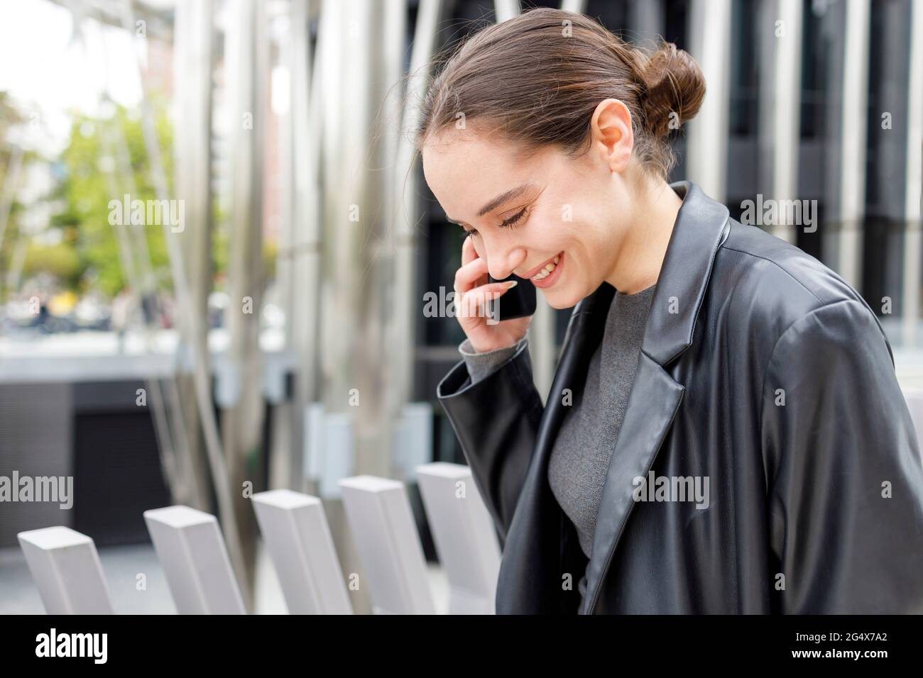 Female entrepreneur smiling while talking on mobile phone Stock Photo