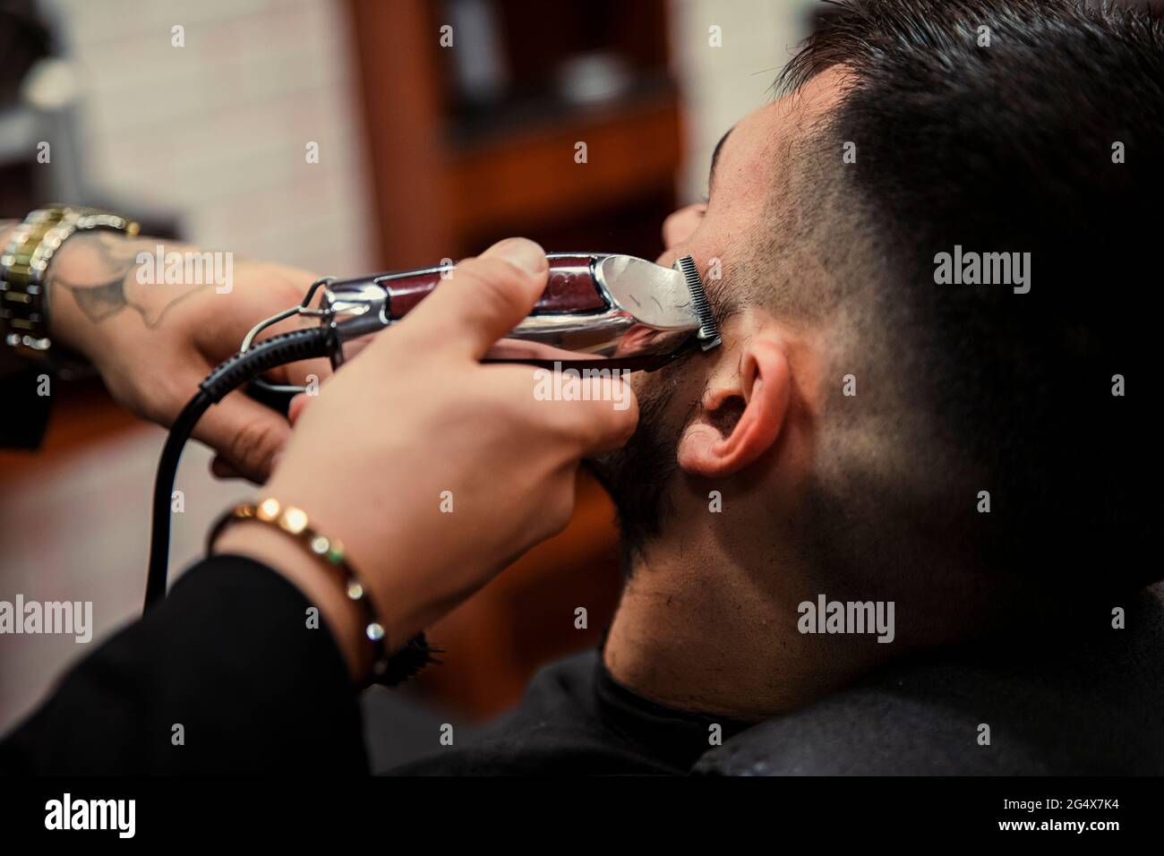 Male barber cutting hair of man with electric razor Stock Photo