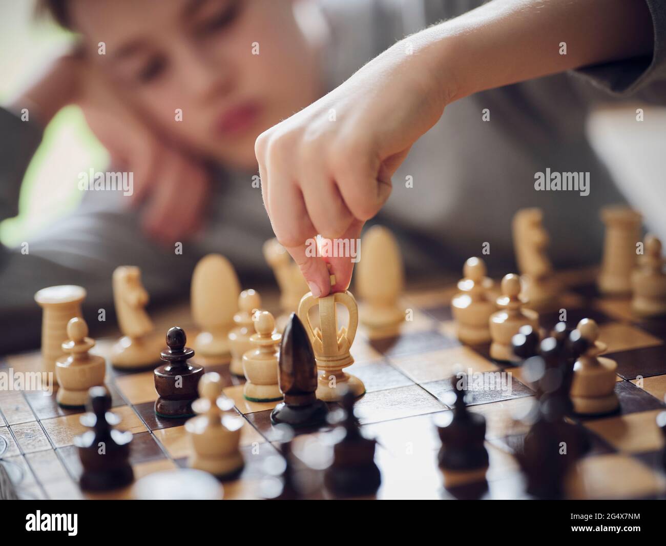 Boy holding chess piece while playing at home Stock Photo