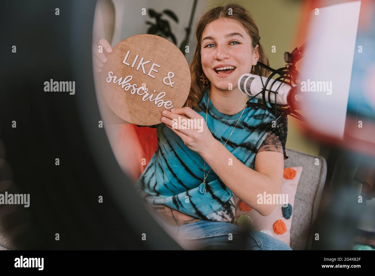 Girl showing like and subscribe sign while vlogging at home Stock Photo