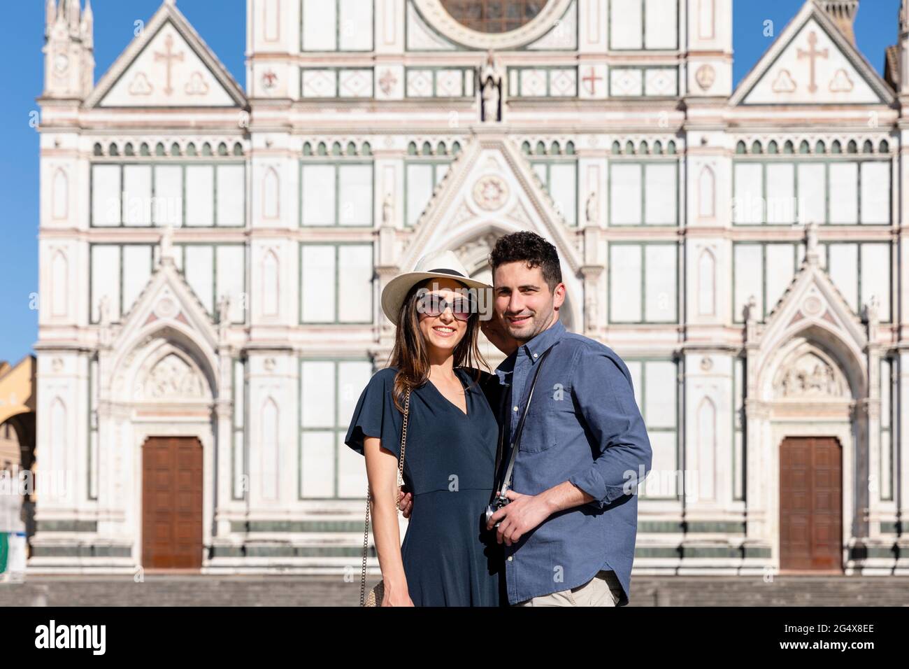 Smiling tourist couple standing in front of Basilica Of Santa Croce, Florence, Italy Stock Photo