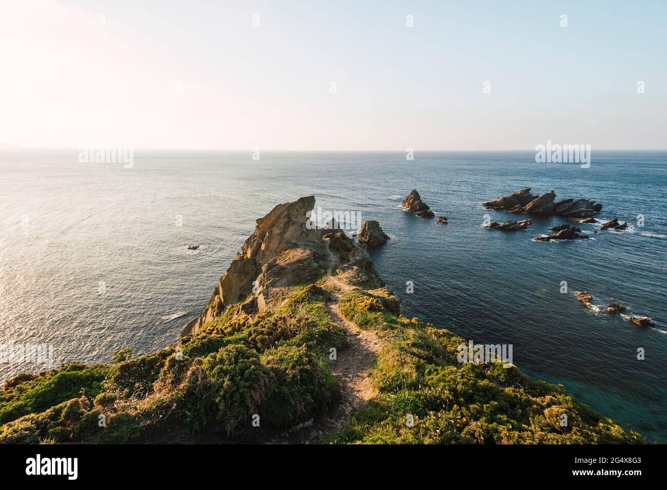 Coastal cliffs at sunset with clear line of horizon over sea in background Stock Photo