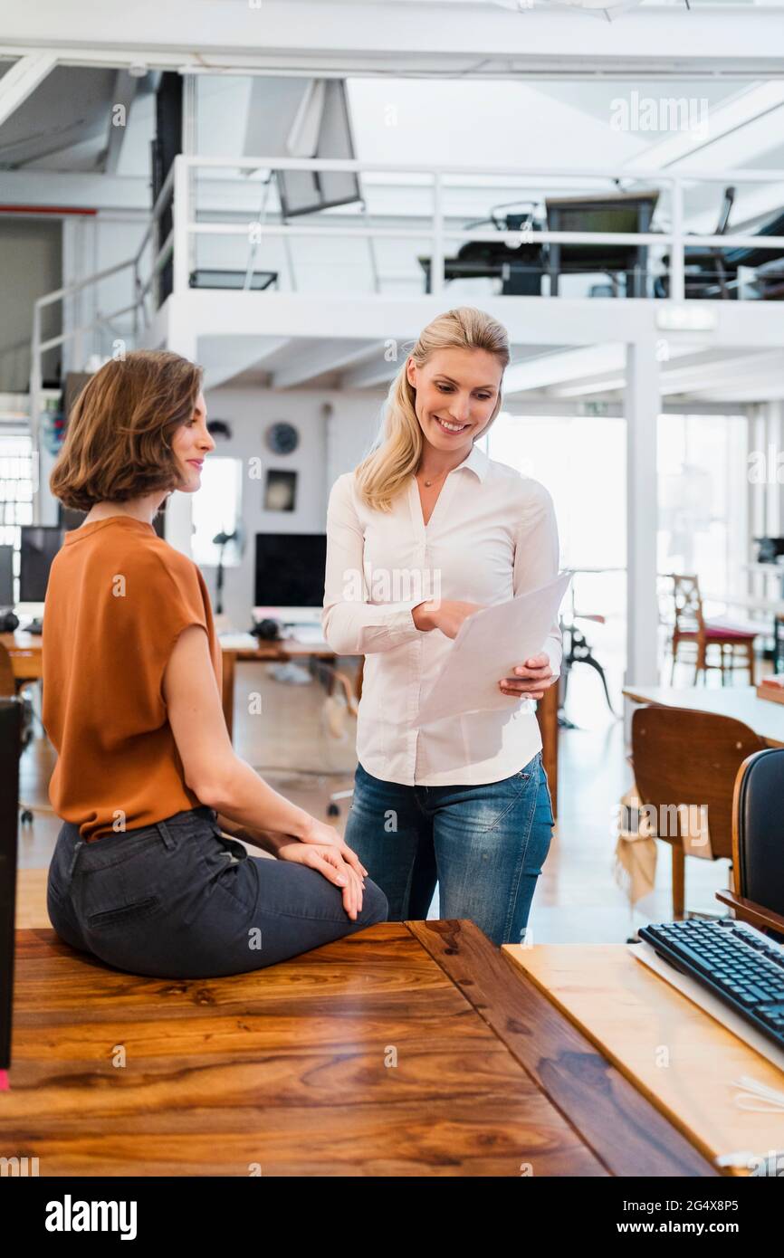 Young female professionals discussing over document in creative office Stock Photo