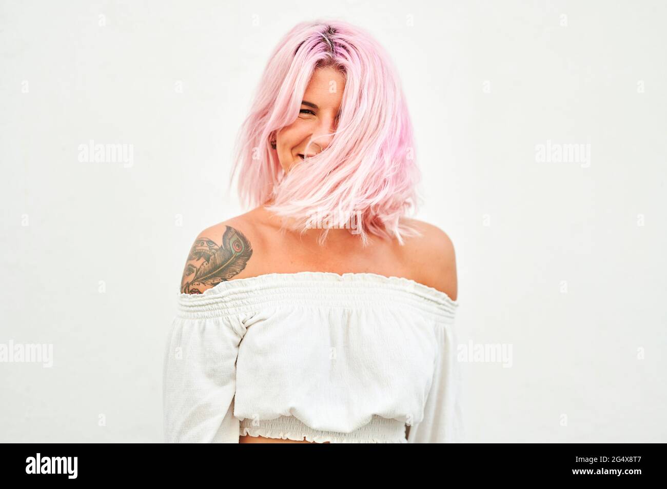 Young woman tossing hair in front of white wall Stock Photo
