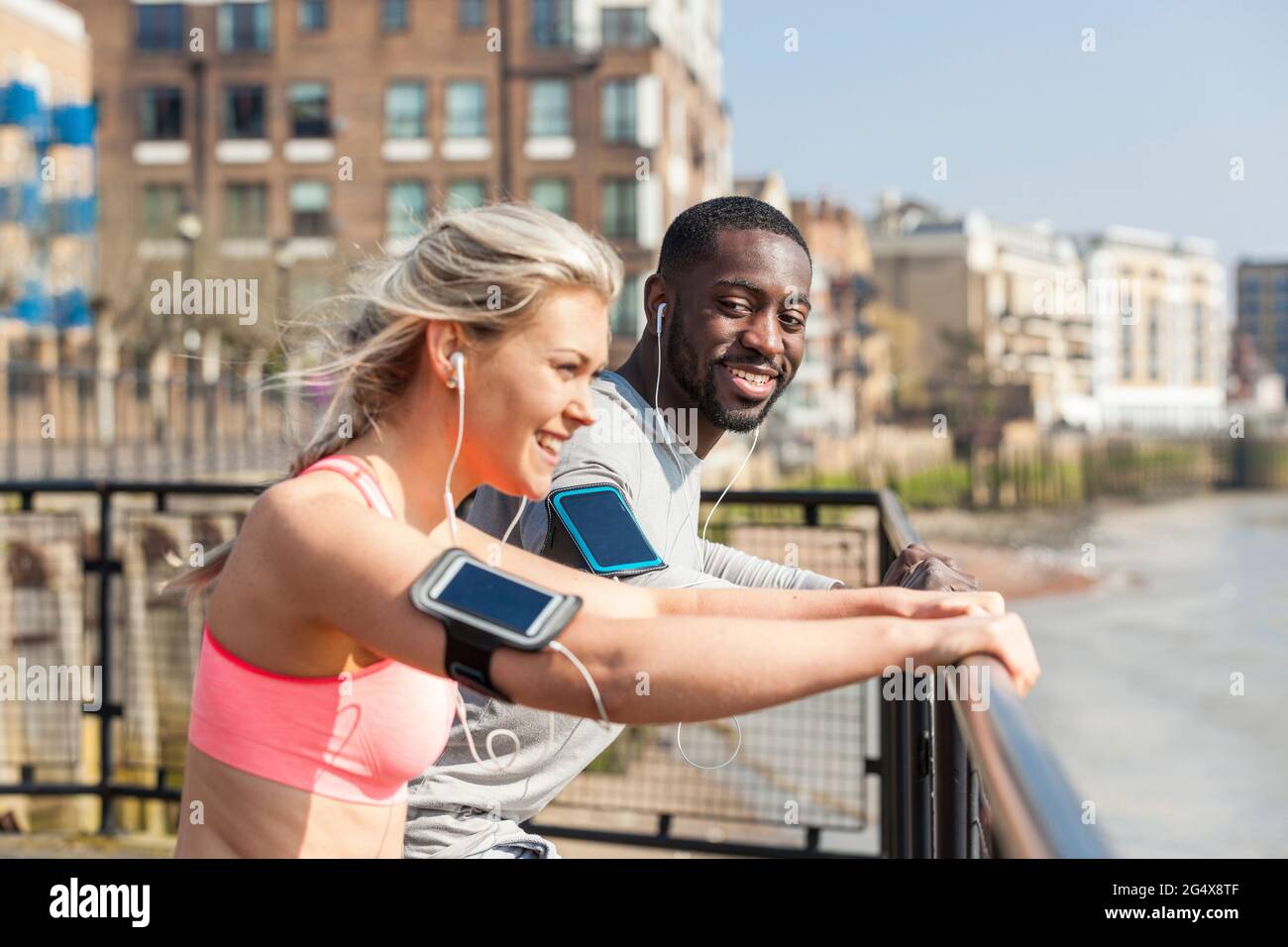 Smiling man and woman leaning on railing while exercising Stock Photo