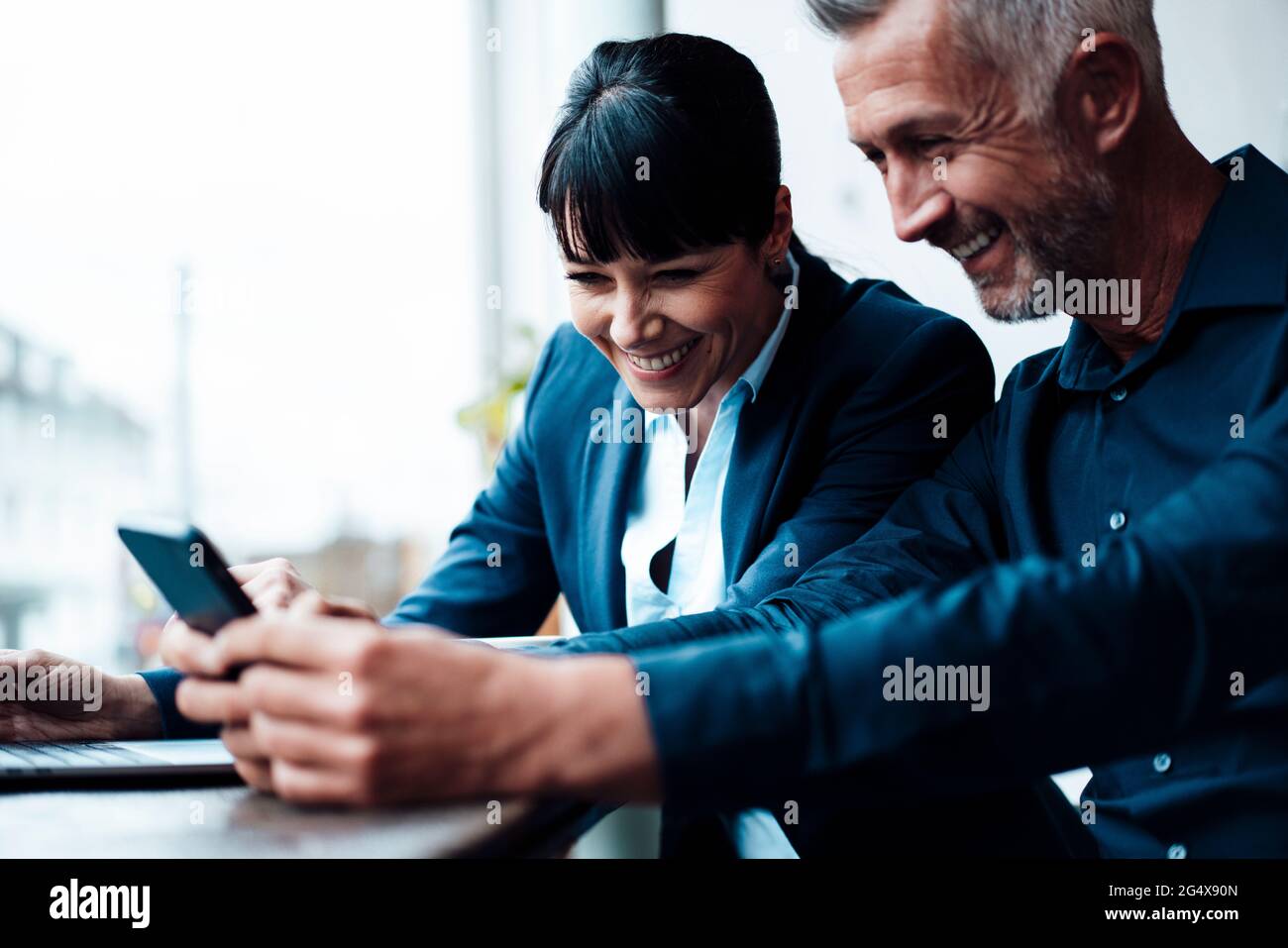 Smiling business couple using mobile phone at cafe Stock Photo
