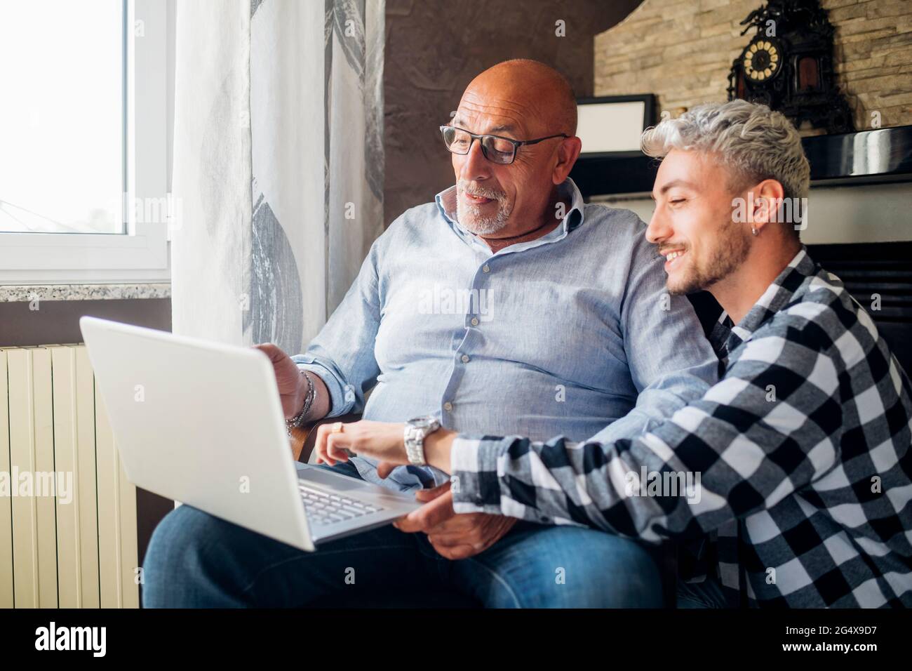 Smiling son guiding father using laptop at home Stock Photo