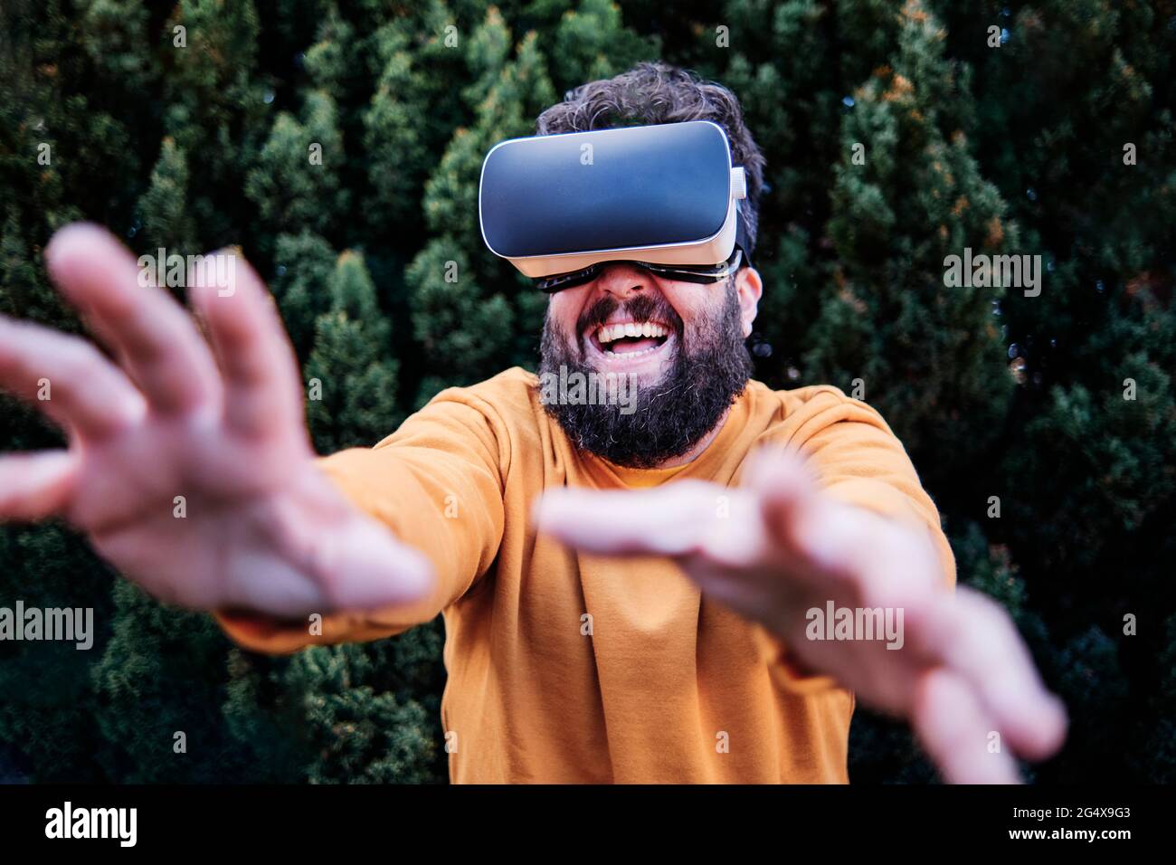 Playful man using VR glasses in garden Stock Photo