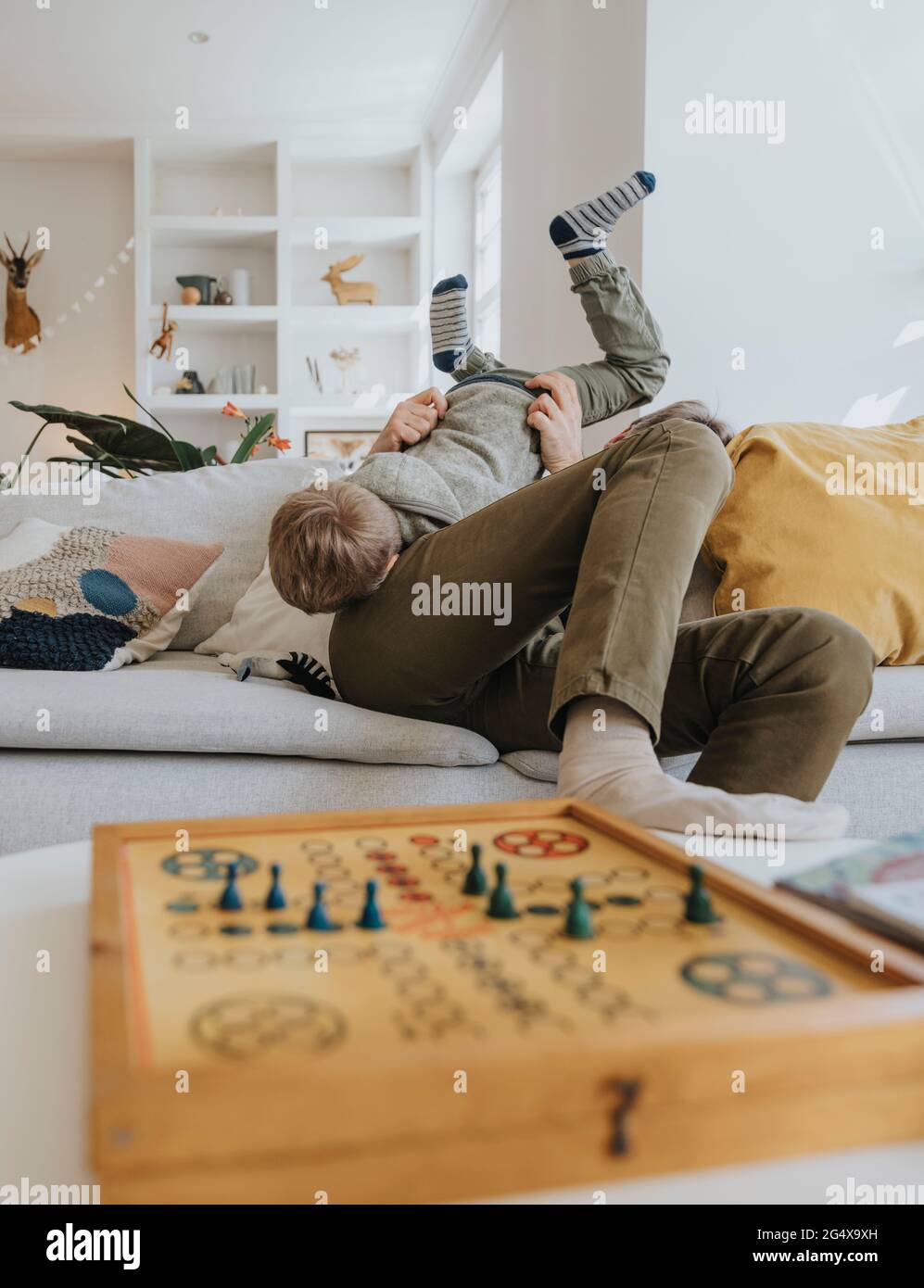 Father playing with son while sitting on sofa at home Stock Photo