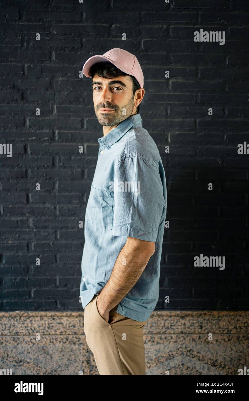 Young man with hand in pocket standing by wall Stock Photo