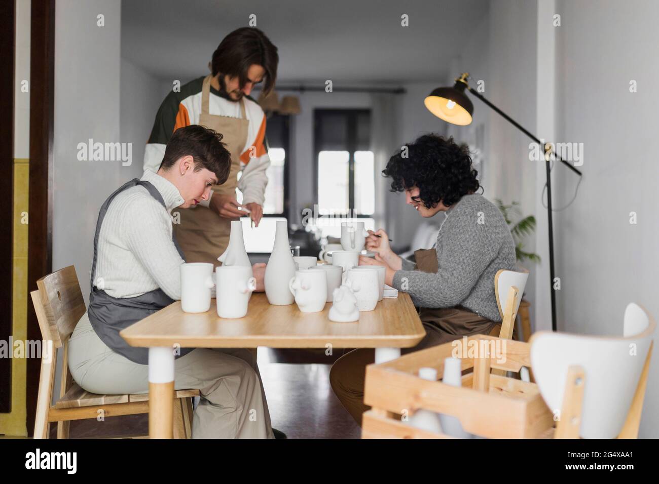 Male and female experts painting ceramics crockery at workplace Stock Photo