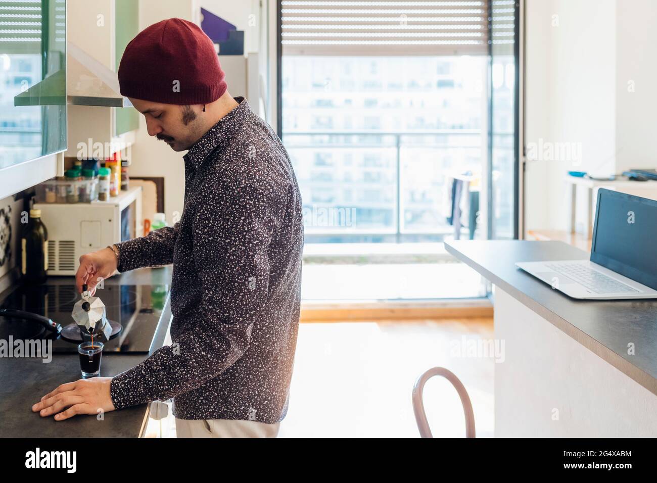 Man pouring coffee in cup at kitchen counter Stock Photo