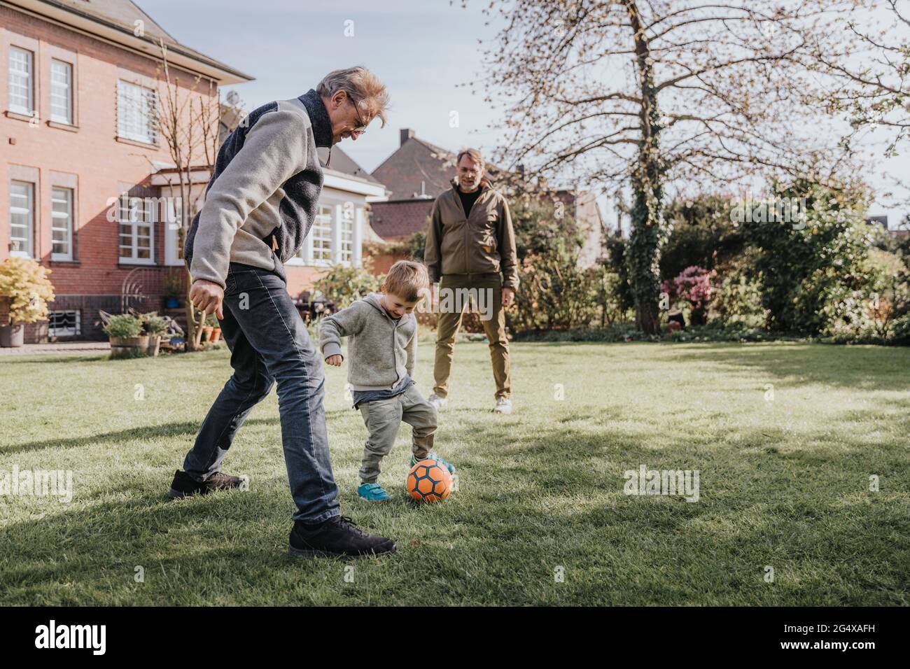 Family playing soccer in backyard Stock Photo