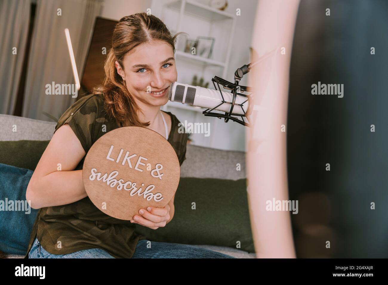 Smiling girl showing like and subscribe sign at home Stock Photo