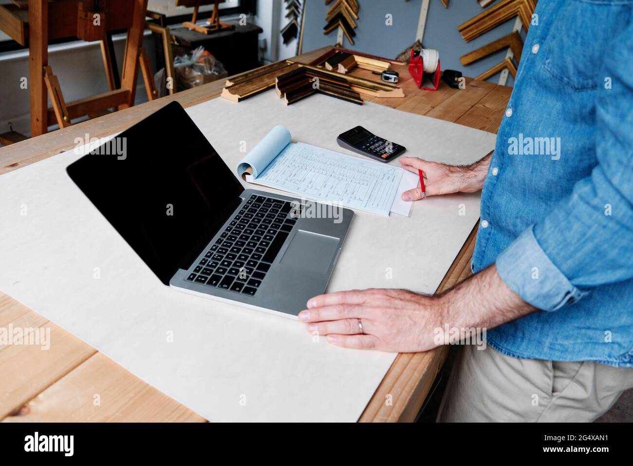 Male frame maker calculating financial bill while working in store Stock Photo
