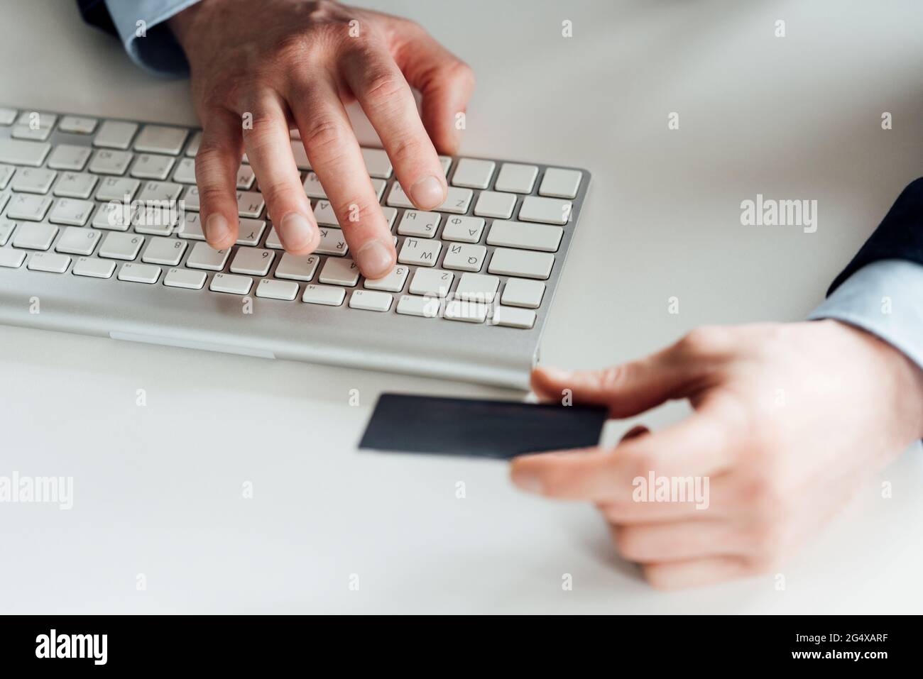 Businessman holding card while typing on computer keyboard in office Stock Photo
