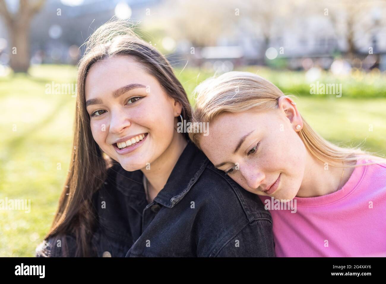 Young woman with head on shoulder of female friend at park Stock Photo