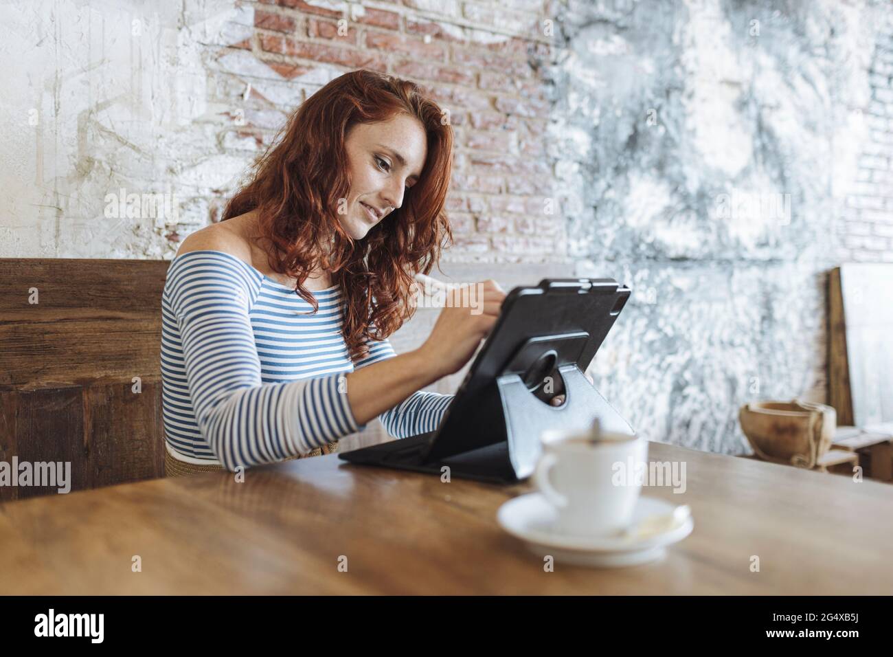 Female graphic designer using tablet while sitting at cafe Stock Photo
