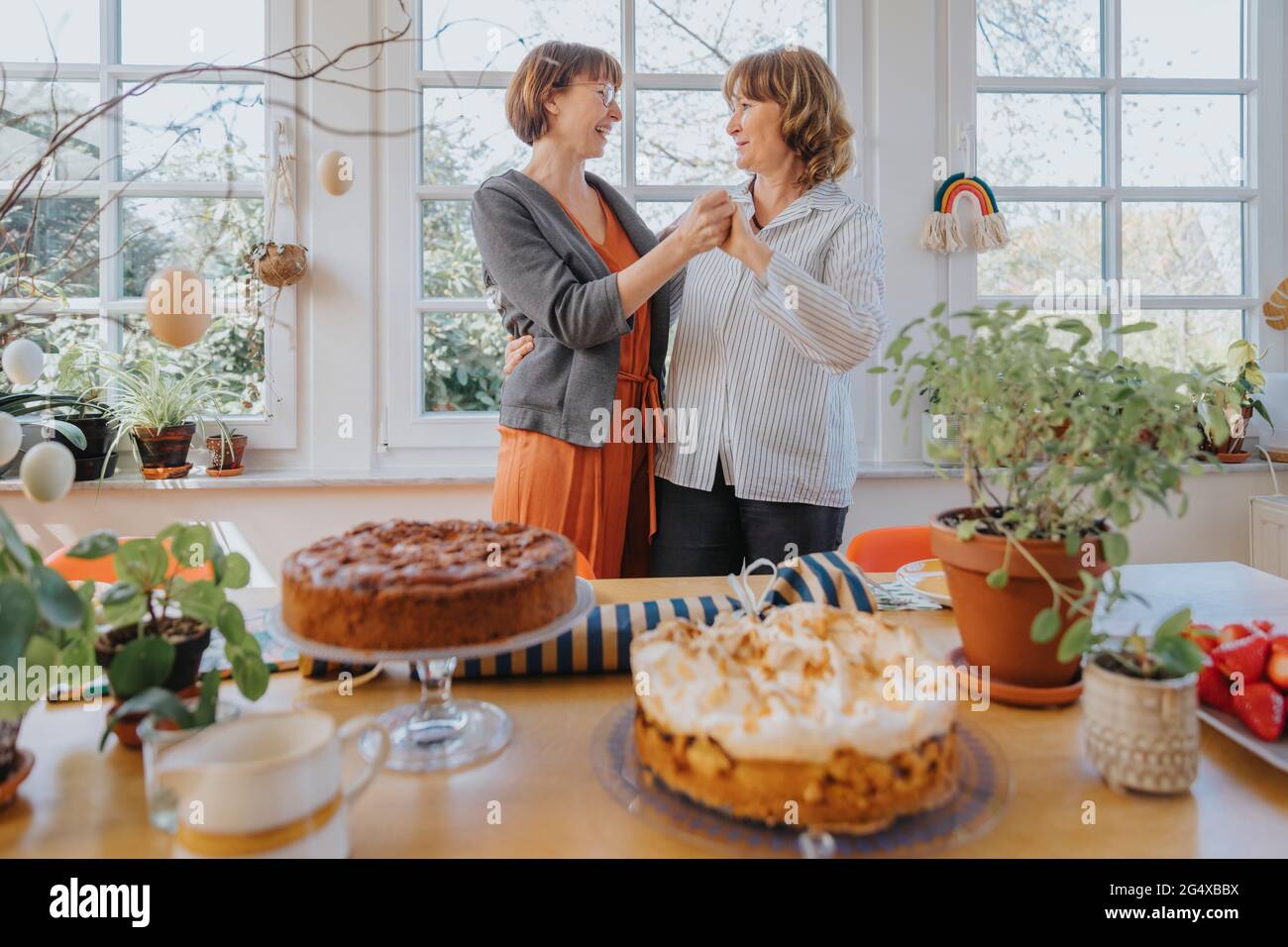 Mother and daughter holding hands while dancing in dining room during Easter Stock Photo