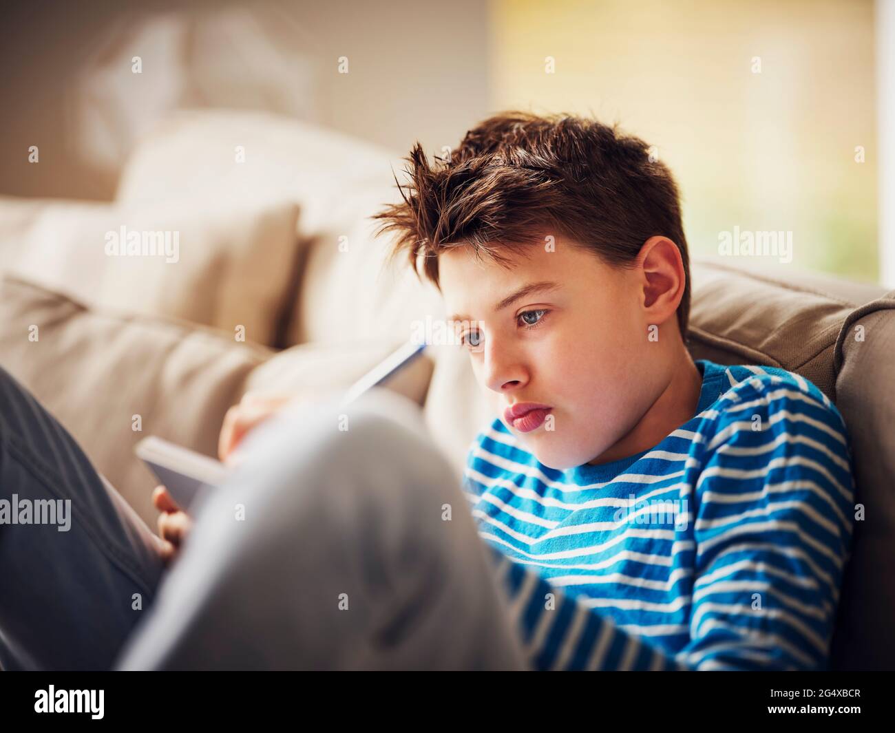 Boy writing on note pad while sitting at home Stock Photo