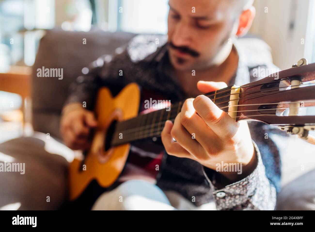 Young male guitarist playing guitar at home Stock Photo