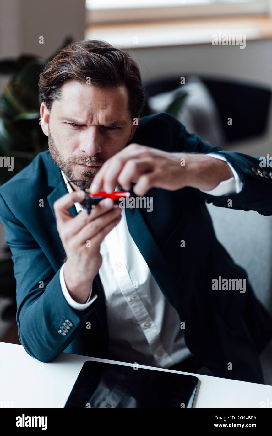 Businessman checking drone while siting at office Stock Photo