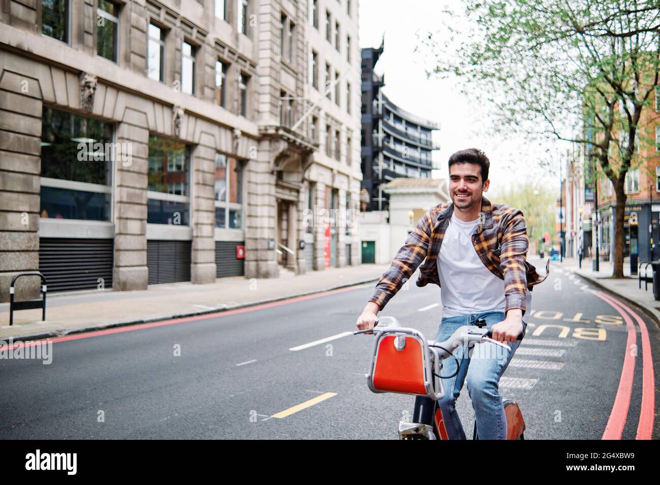 Smiling young man cycling on road in city Stock Photo