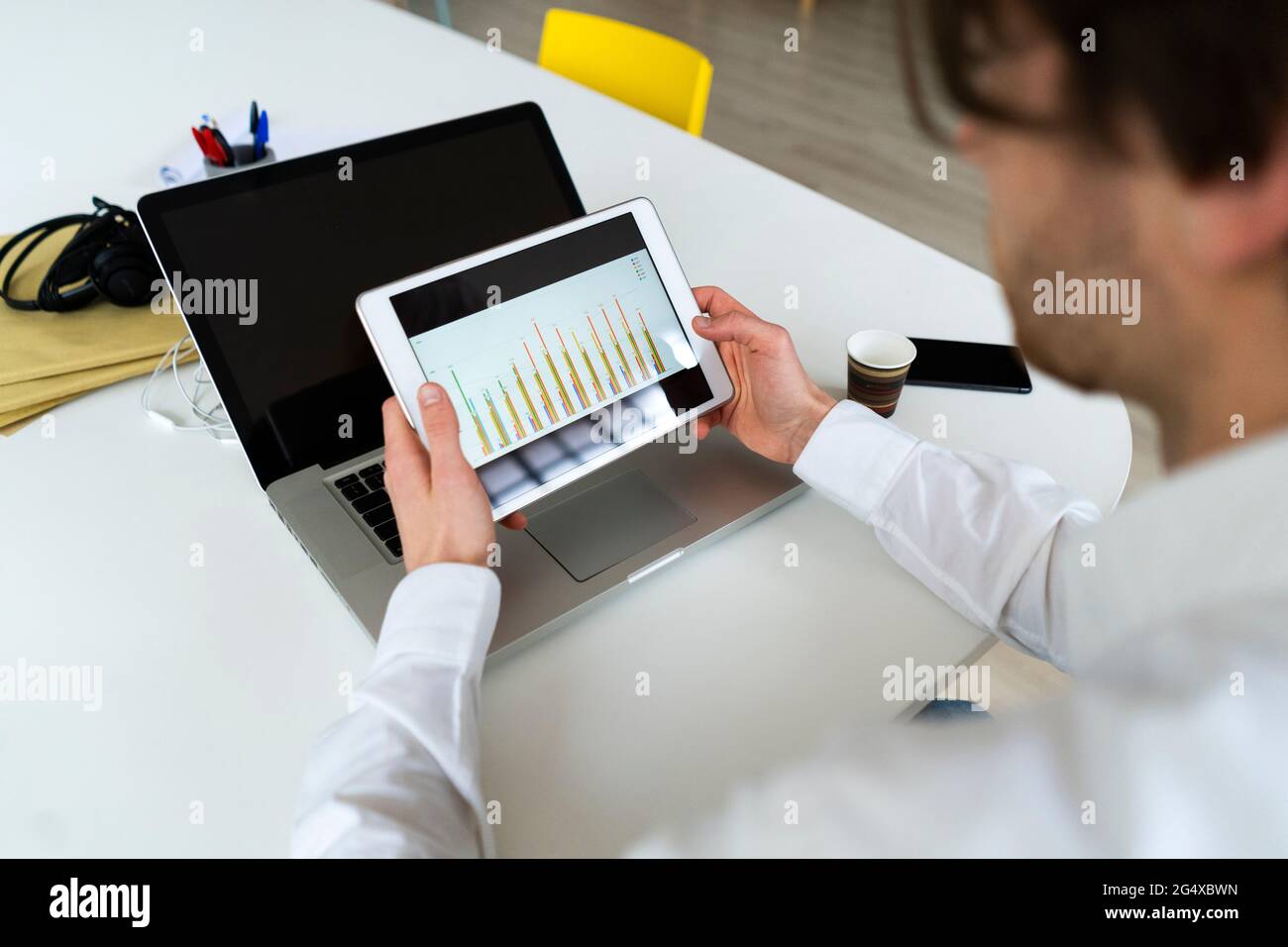 Male entrepreneur checking graph on digital tablet while working at office Stock Photo