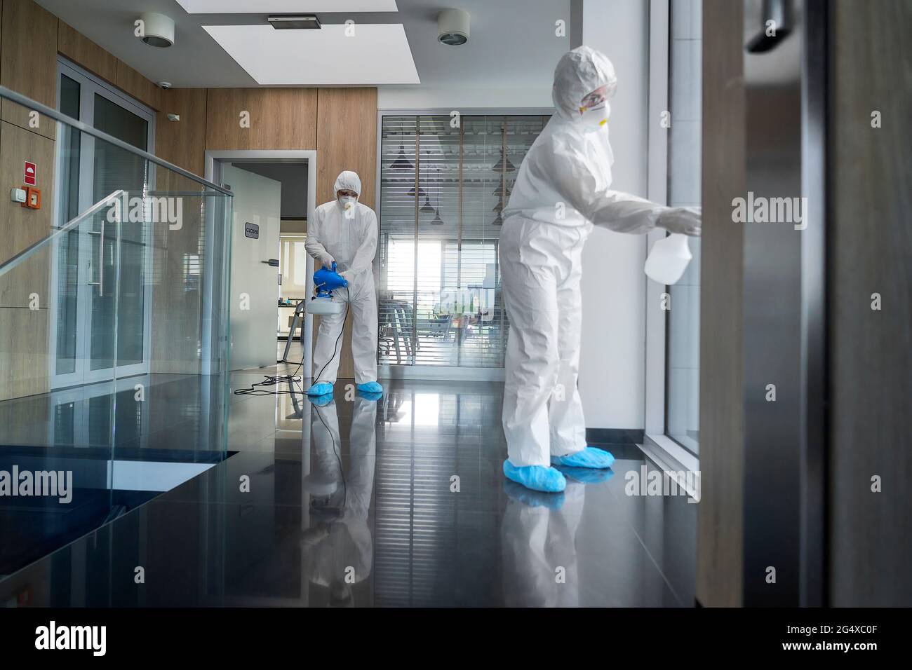Sanitation workers disinfecting office corridor Stock Photo