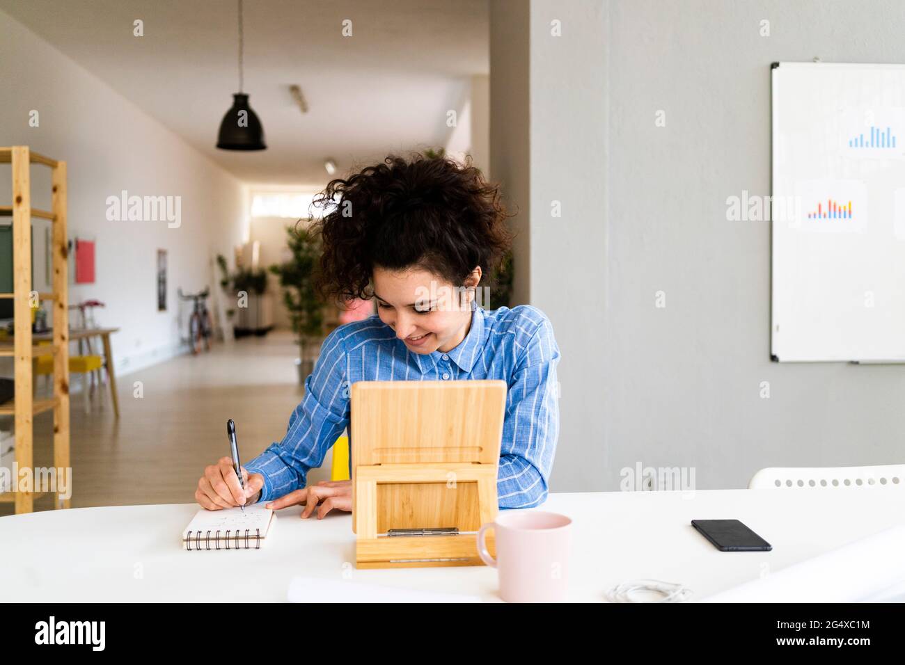 Businesswoman smiling while working in creative office Stock Photo