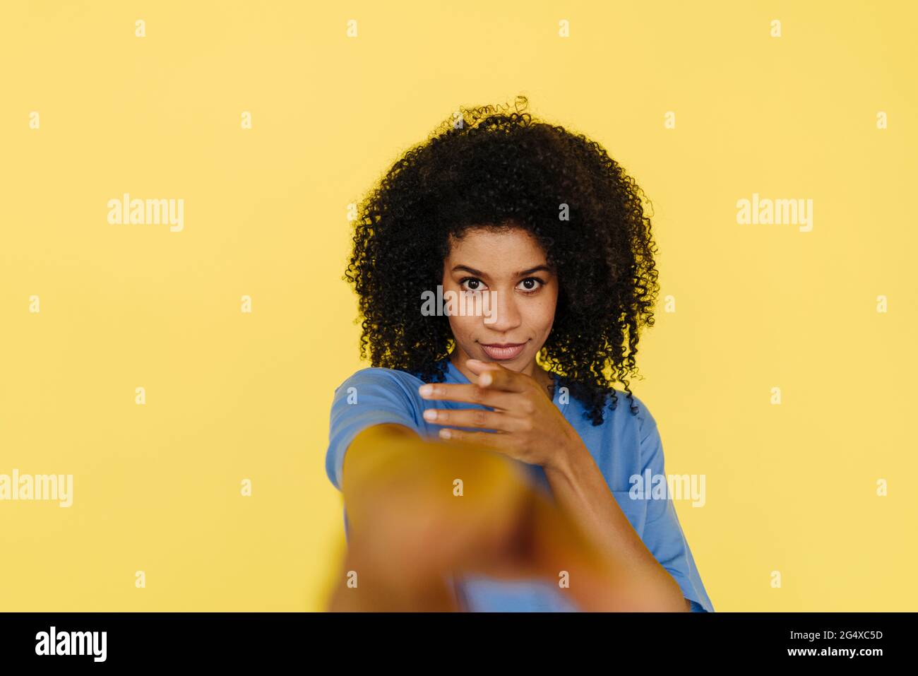Afro woman gesturing in front of yellow background Stock Photo - Alamy