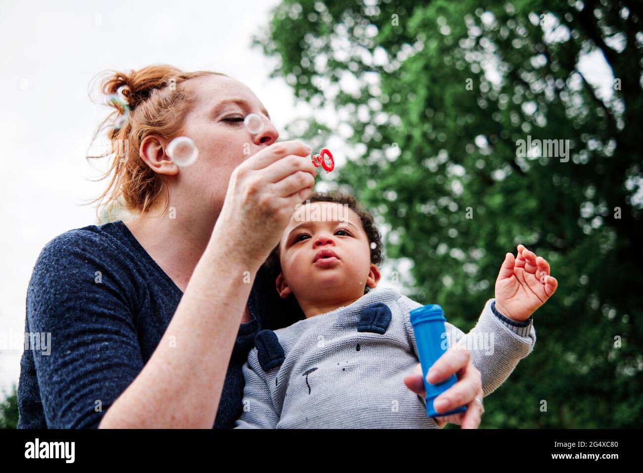 Mother Blowing Bubbles With Son At Park Stock Photo Alamy
