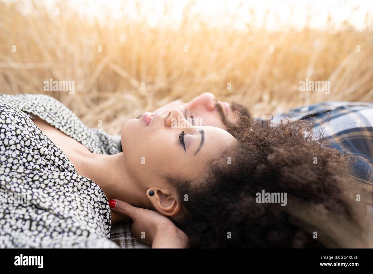 Couple napping while lying on field Stock Photo